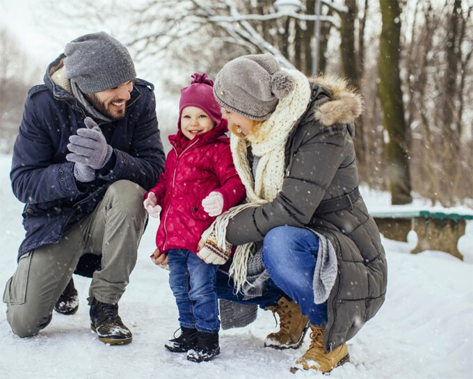 father and mother with toddler in the snow