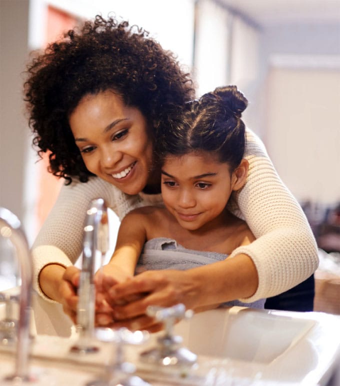mother helping daughter wash her hands