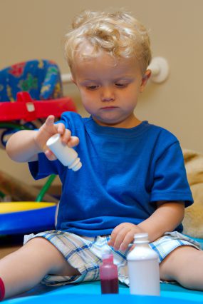 young child playing with medication bottles