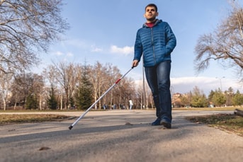 visually impaired man walking outside using a cane