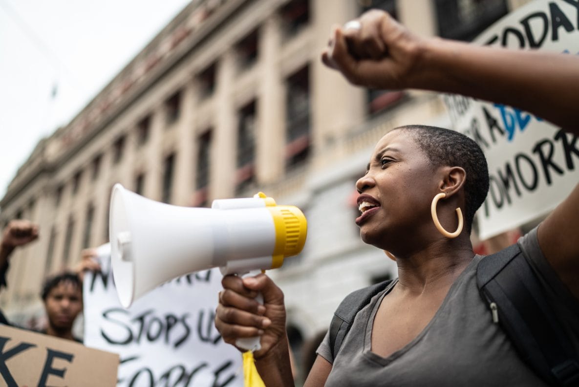 black woman using a megaphone at a demonstration