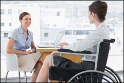 The figure above is a photograph showing two women talking in an office. One woman is in a wheelchair.