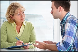 The figure above is a photograph showing a female medical professional counseling a young man.
