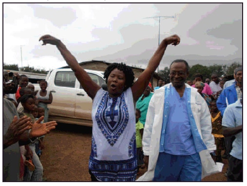 The figure above is a photograph of an Ebola survivor, accompanied by a medical director, being welcomed by her community in Firestone District, Liberia, in 2014.