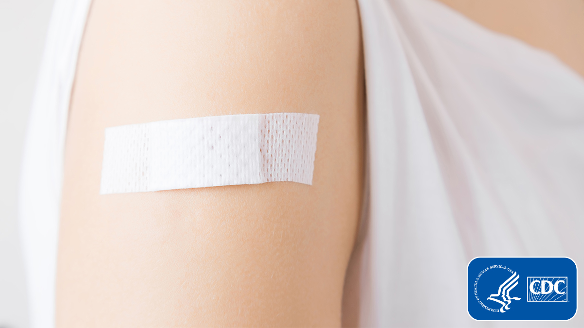 The figure is a photo of an arm with a small bandage on the shoulder with the CDC logo overlaid in the right corner.