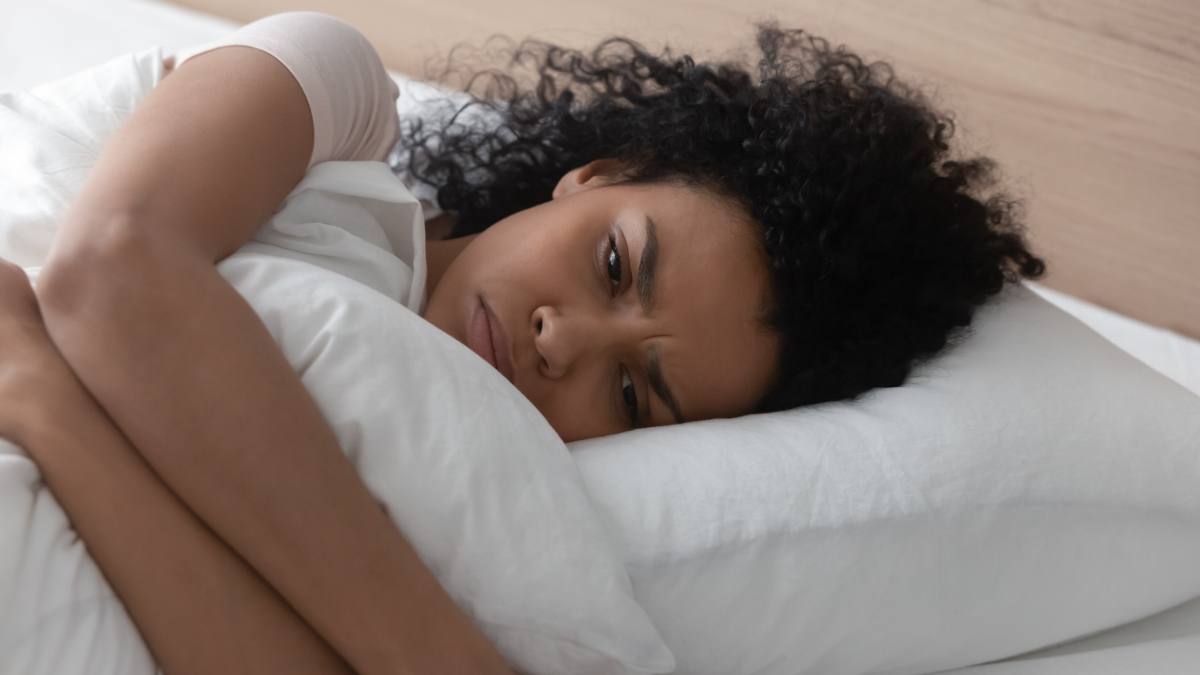 The figure is a photo of a woman in bed holding a pillow.