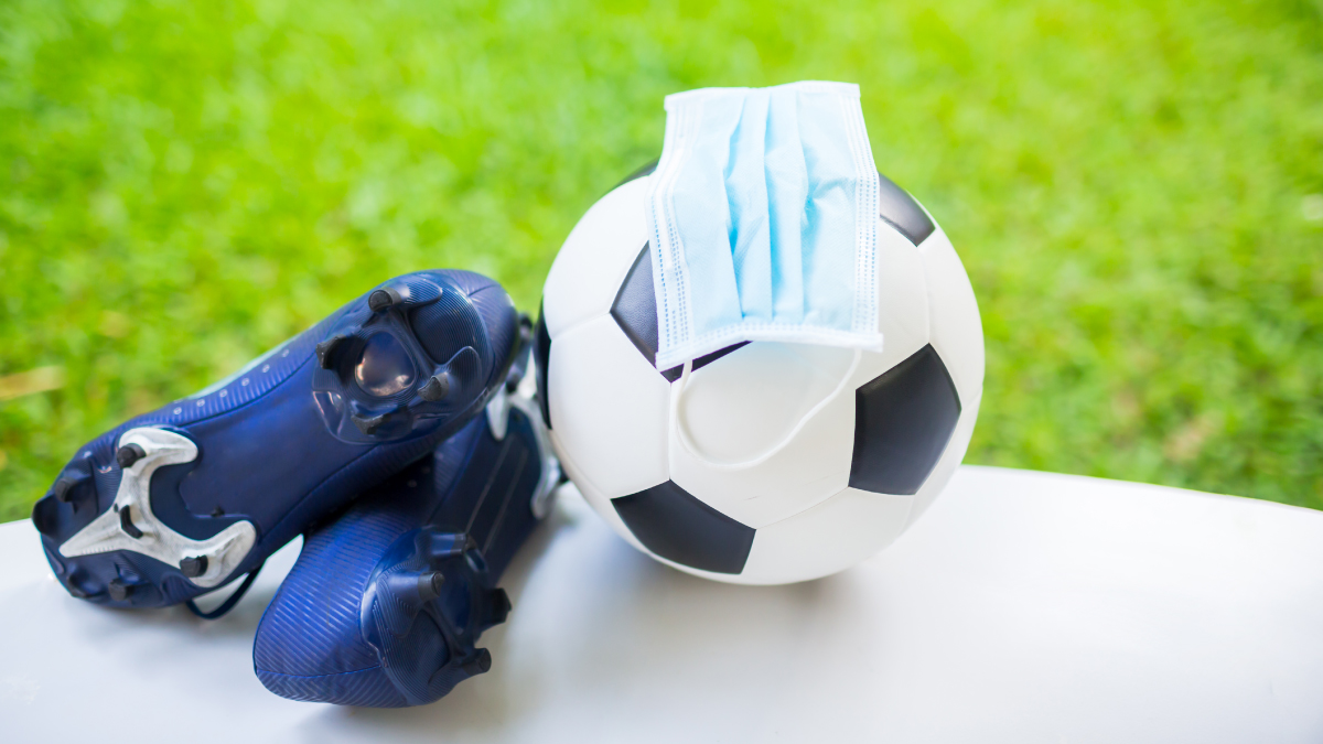 The figure is a photo of soccer cleats and a mask on a soccer ball near a field.
