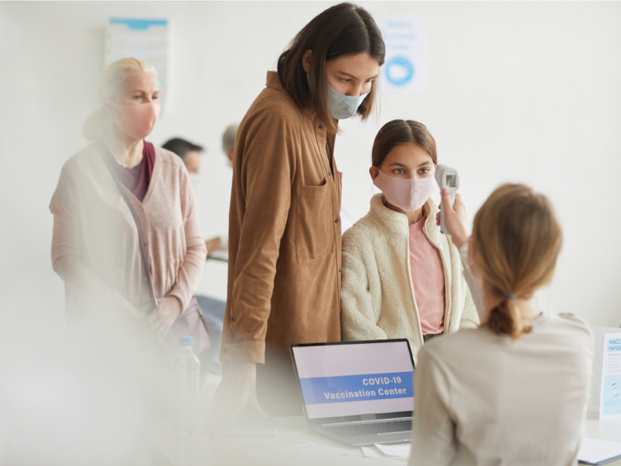 COVID-19 Vaccine Provider Access and Vaccination Coverage Among Children Aged 5–11 years — United States, November 2021–January 2022 The figure is a photo of a parent and child checking in at a COVID-19 vaccination clinic.