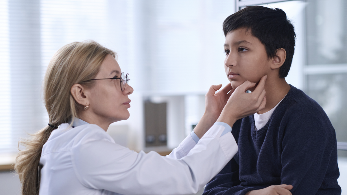 The image shows a clinician examining a child&rsquo;s throat.