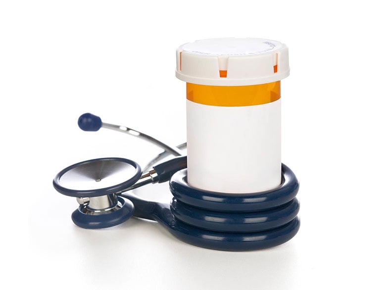 A stethoscope wrapped around a prescription bottle.