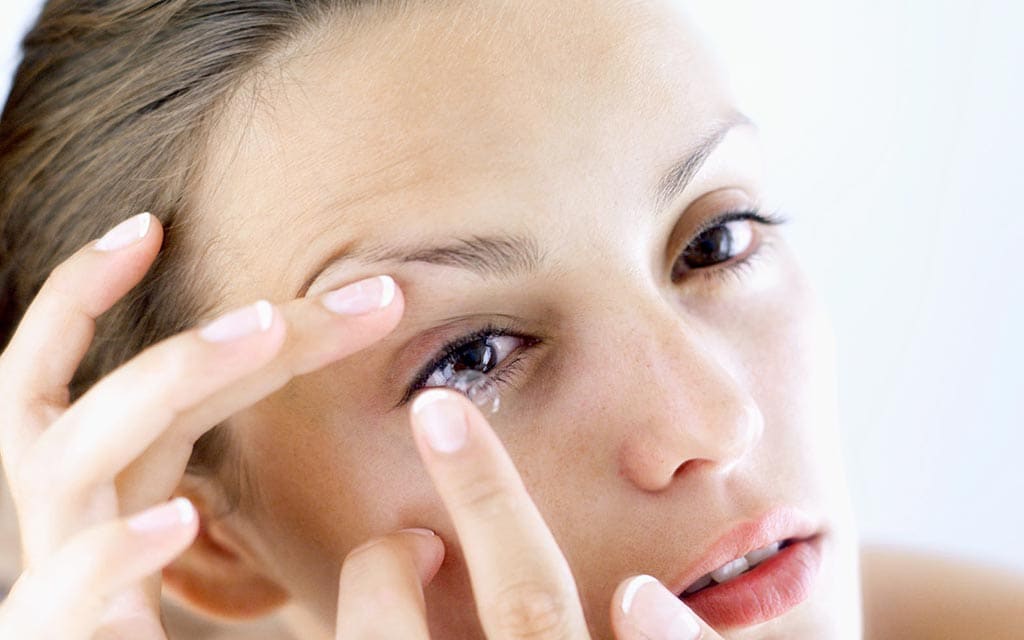 Young lady inserting a contact lense.