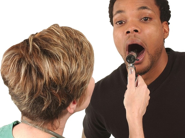 A doctor examinig a man's throat.