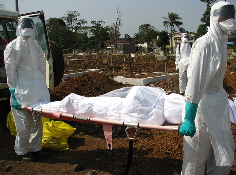 Medical workers carry a body of an Ebola victim for burial on a stretcher