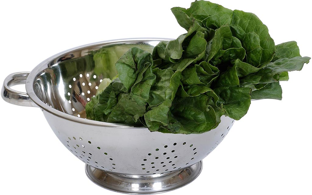 Raw spinach sitting in a colander.