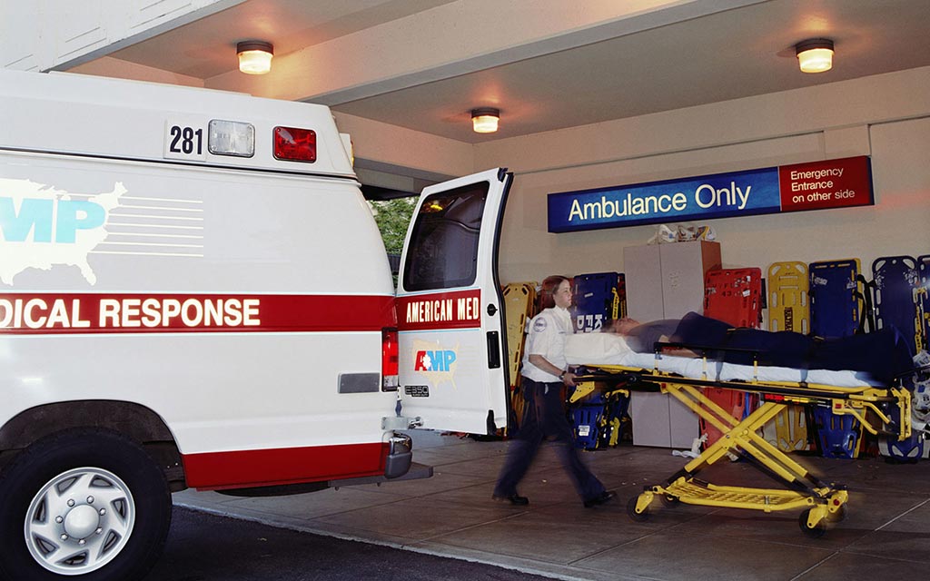 An EMS vehicle arriving at a hospital and the worker is transporting a patient into the emergerncy room.