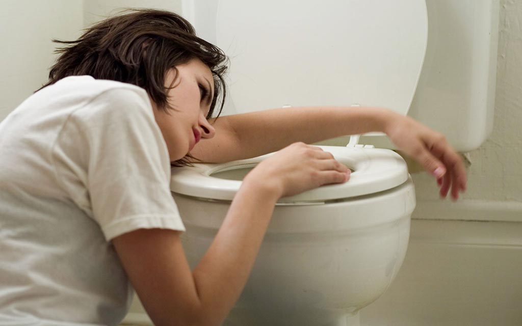 A sick student resting her head on a toilet seat