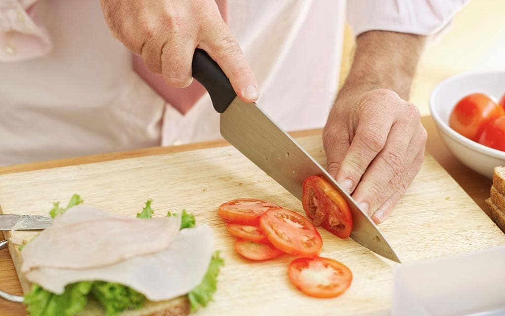 A person making a sandwich on a cutting board.