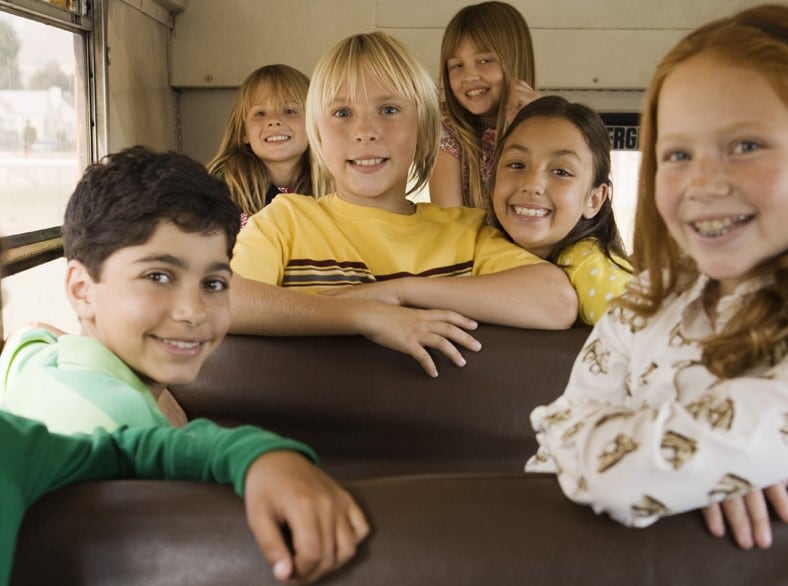 A group of kids sitting on a school bus.
