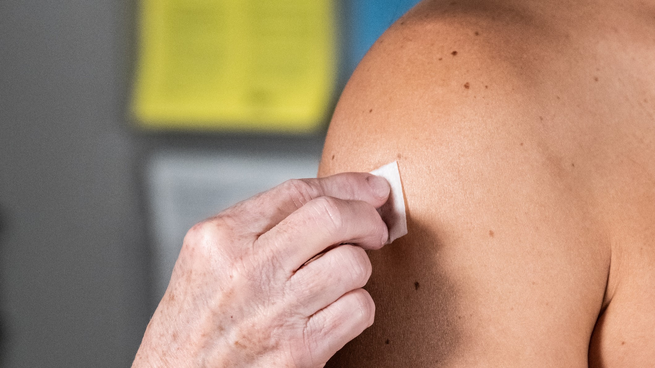 a healthcare provider cleans the skin on a patient's arm before a vaccine