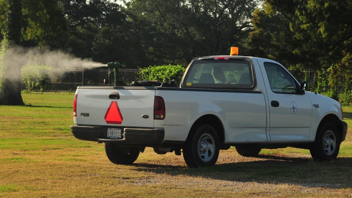 Mosquito control truck spraying insecticides into the air.