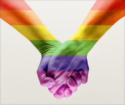 Close-up photo of two mens hands held together with pride colors superimposed on their skin