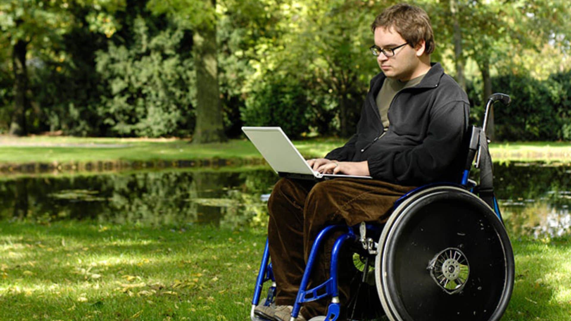 Teen boy in wheelchair looking at laptop