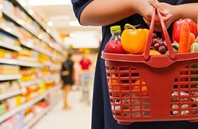 Person holding shopping basket full of food