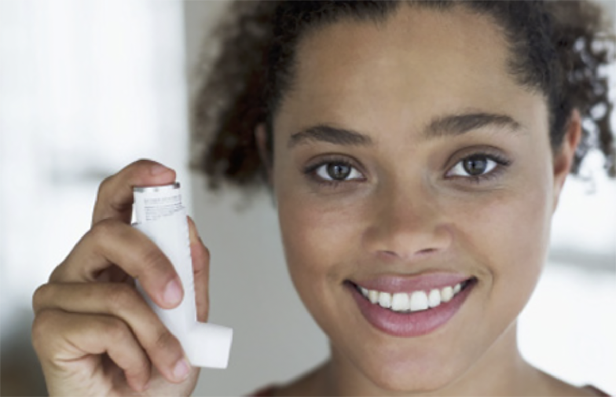 Young woman holding an inhaler in her right hand.