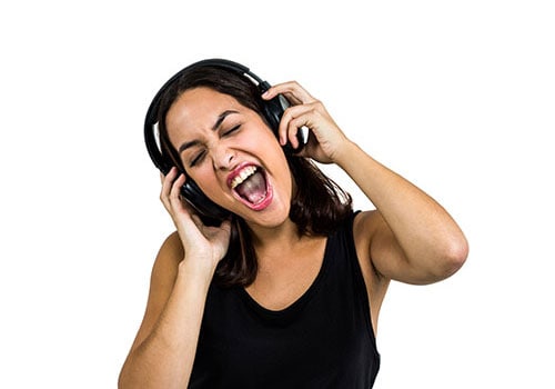 Woman wearing headphones and singing. Her hands are on each earpiece.