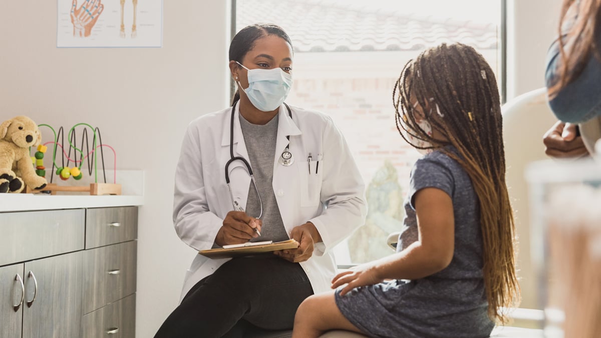 A doctor talks with a young girl and her mother.