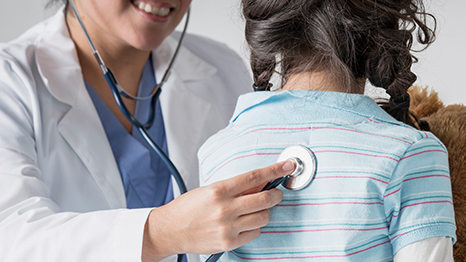 A healthcare provider listens to the lungs of a young girl.