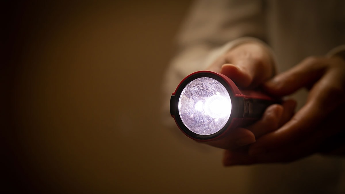 Person holding a lit flashlight.