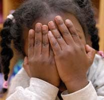 Young black girl hiding her face with her hands