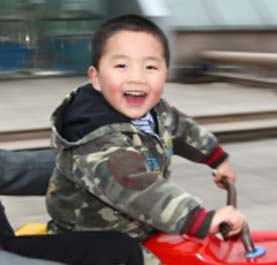 A little boy riding his toy car