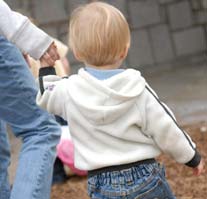 A toddler holding his care-givers hand while walking