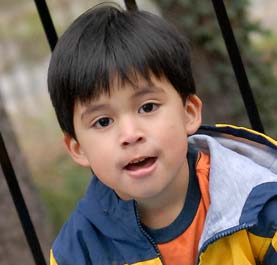 A young boy in a jacket playing outside. 