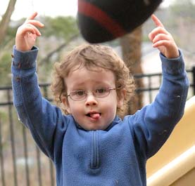 A boy throwing a football with his hands up