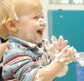 A young boy playing in cake icing
