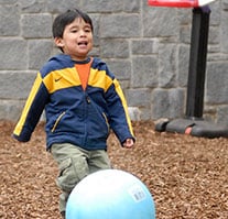 A toddler boy playing with a ball