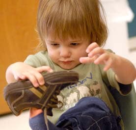 A young boy inspecting his shoe
