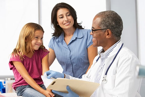 Doctor examining young girl with mother present