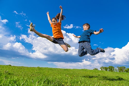 Dos niños saltando en verdes colinas