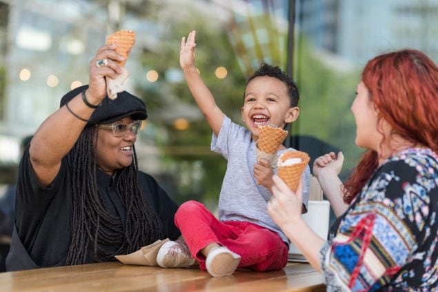 Kid raises hand while eating ice cream