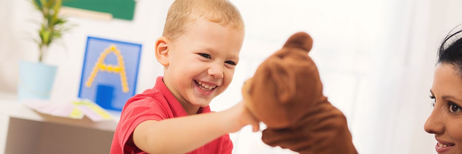 A young boy playing with a stuffed animail