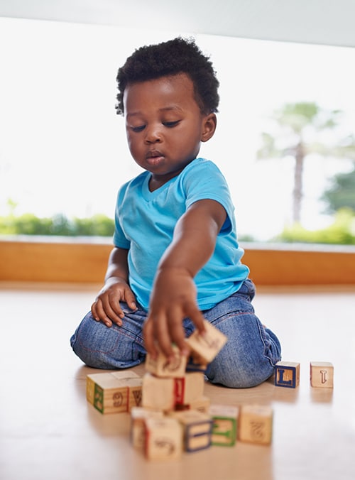 Boy having fun and learning all in one with blocks