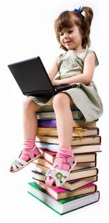 Photo: girl sitting a stack of books playing on a computer