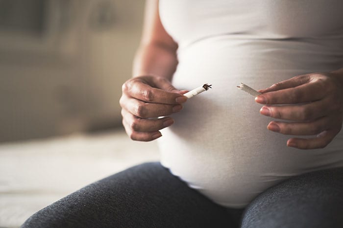 Pregnant woman breaking cigarette