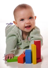 Baby with big smile with blocks