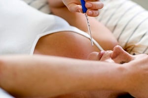 Pregnant woman taking her temperature with a thermometer