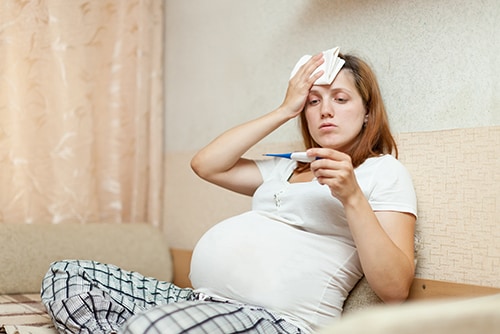 pregnant woman with thermometer in home